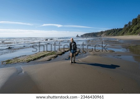 Woman hiking on Shi Shi Beach and Trail in Olympic National Park, Washington on sunny summer afternoon.