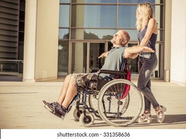 Woman and his boyfriend on the wheelchair going out. concept about diseases and people