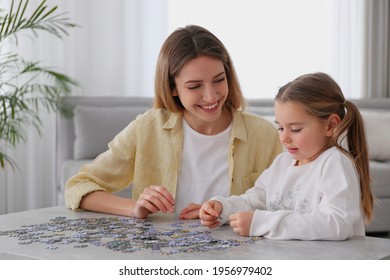 Woman and his little daughter playing with puzzles at home
