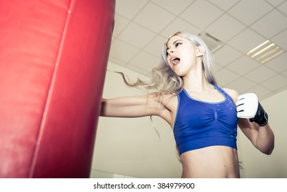 Woman Hits The Boxing Heavy Bag In The Gym. Hard Mixed Martial Arts Training