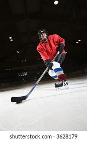 Woman Hockey Player Skating On Ice Lining Up To Shoot Puck.