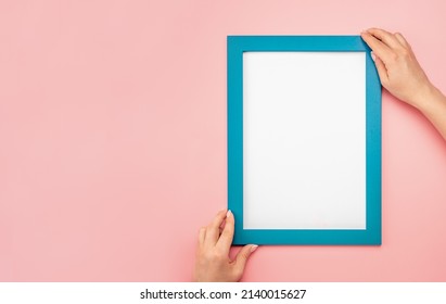 Woman Hold Blank Diploma Frame On Pink Wall Background. Hanging Photo Frame Mockup On Pink Wall. Picture Frame Mockup. Holding Frame. Female Hands Hold Mockup With White Paper. Copy Space