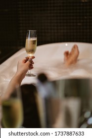 Woman Hold Cold Wineglass By Hand In Bathtub With Hot Water And Soap Bubbles , Seeing Her Feet As Background