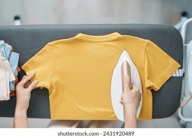 Woman hold Electric hot iron press T shirt clothes on ironing board, Intelligent automatic steam iron. Laundry, Housework, Housekeeping, Domestic hygiene, household of chores and daily routine concept - Powered by Shutterstock