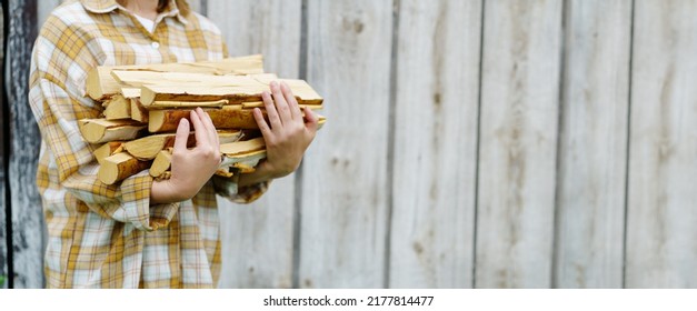 Woman hold firewood. Horizontal concept with firewood in the hand of a woman, takes care of the firewood in the cold house to light the fireplace. Rustic countryside background warmth and firewood. - Shutterstock ID 2177814477
