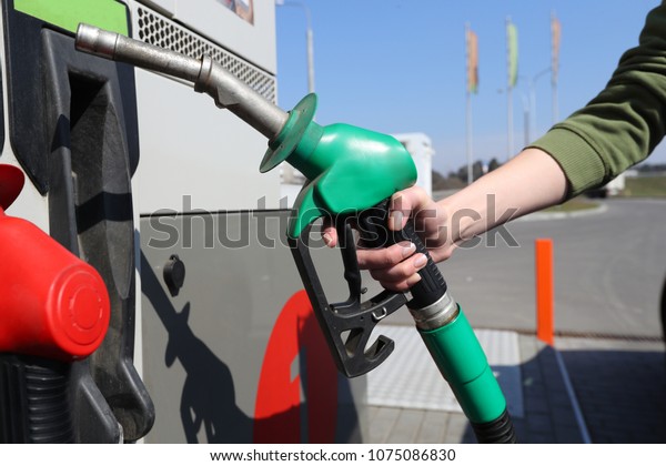 Woman\
hold fuel nozzle to add fuel in car at gas\
station