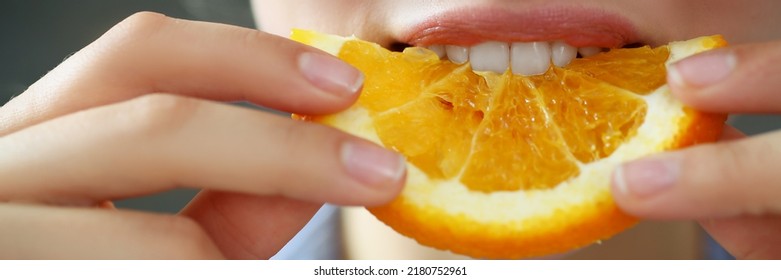 Woman Hold In Hand Slice Of Chopped Orange Eats For Breakfast With Mouth In Kitchen