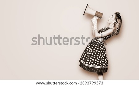 Woman hold mega phone megaphone, shout advertising offer. Girl wear pin up style dress in polka dot yelling megaphone loudspeaker. Brown toned monochrome bw photo. Female model in retro vintage studio