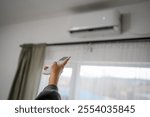 Woman hold a remote control with air conditioner.Turn on the air conditioner to cool down.