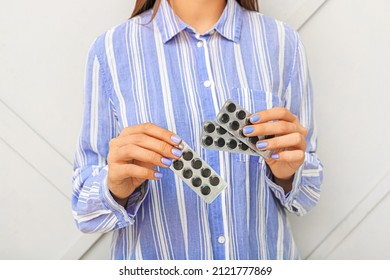 Woman holding activated carbon pills near wall
