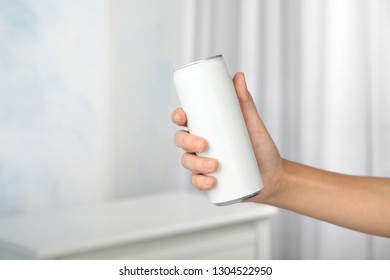 Woman holding aluminum can with beverage on blurred background, closeup. Space for design