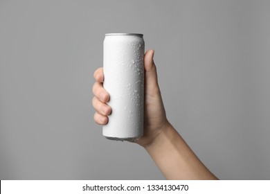Woman holding aluminum can with beverage on grey background, closeup. Space for design