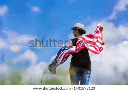 Woman holding the american flag outdoors on a meadow.  4th of July - Independence day. 