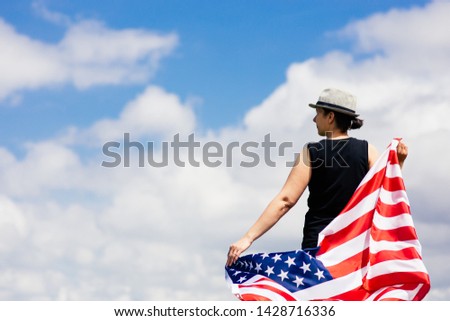 Woman holding the american flag outdoors on a meadow.  4th of July - Independence day.