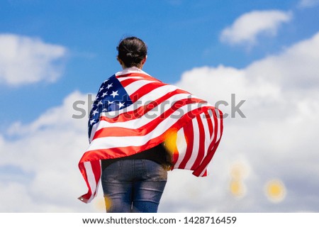 Woman holding the american flag outdoors on a meadow.  4th of July - Independence day.