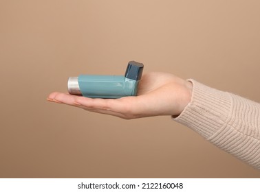 Woman Holding Asthma Inhaler On Brown Background