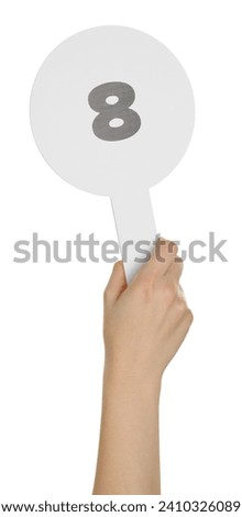 Woman holding auction paddle with number 8 on white background, closeup
