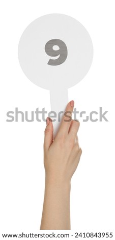 Woman holding auction paddle with number 9 on white background, closeup