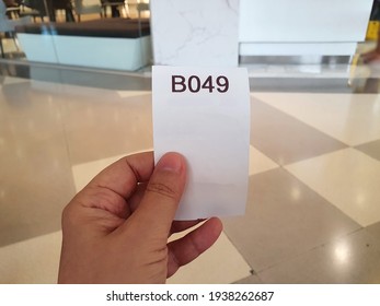 A Woman Holding A B 049 Paper Queue From The Machine Waits For A Transaction, Such As Taking Money To Pay Bills Or Depositing Cash In Your Account In A Bank, Service Center, Government Agency,hospital