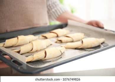 Woman Holding Baking Sheet With Raw Croissants Indoors