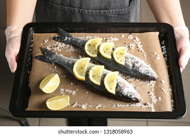 Woman Holding Baking Sheet With Raw Seabass Fish, Closeup