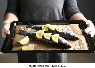 Woman Holding Baking Sheet With Raw Seabass Fish, Closeup