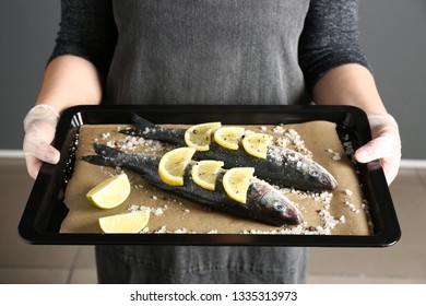 Woman Holding Baking Sheet With Raw Seabass Fish, Closeup