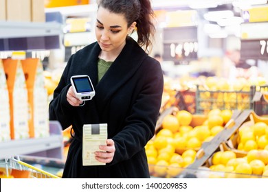 Woman Holding Bar Code Scanner And Scanning Products In Store.