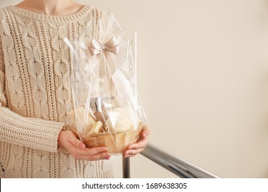 Woman Holding Basket With Gifts For Mother's Day Indoors