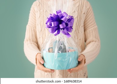 Woman Holding Basket With Gifts For Mother's Day On Color Background