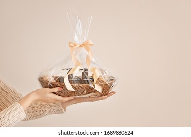 Woman Holding Basket With Gifts For Mother's Day On Light Background