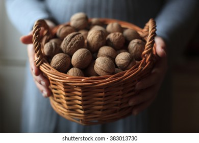 A Woman Holding A Basket With Walnuts