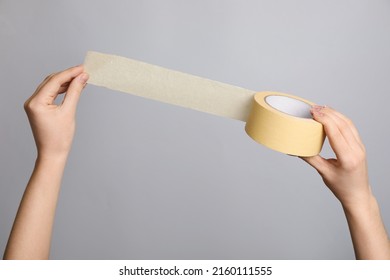 Woman holding beige adhesive tape on light grey background, closeup - Shutterstock ID 2160111555