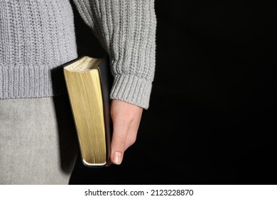 Woman Holding Bible Against Black Background, Closeup. Space For Text