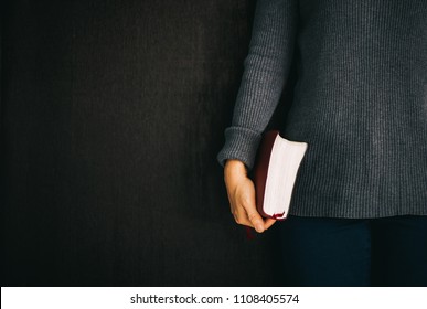 Woman Holding The Bible In Hands On Black With Copy Space.