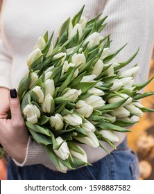 Woman holding big beautiful blossoming mono bouquet of fresh white tulips flowers. Fresh white tulips bouquet. Beautiful flowers
