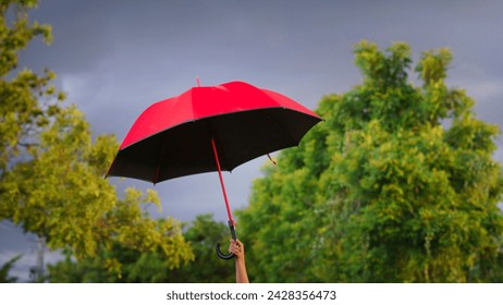 woman holding a big red umbrella On a day when the sky was overcast, and windy it seemed like a storm was about to happen.