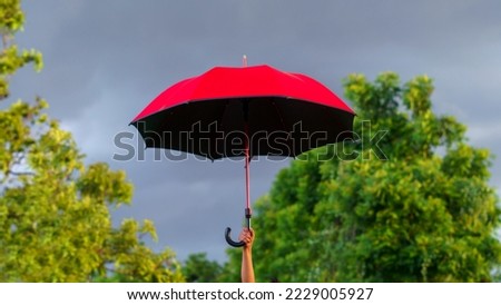 woman holding a big red umbrella On the day when the sky was overcast, it seemed like a storm was about to happen.