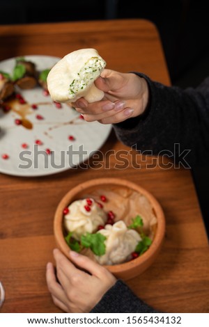 Woman is holding a bitten georgian traditional khinkali with cottage cheese and herbs with hand