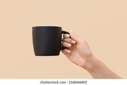 Woman holding black cup on color background, closeup