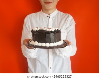 Woman holding a black forest cake on plate over red background - Powered by Shutterstock