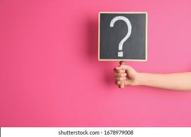 Woman holding blackboard with question mark on pink background, closeup. Space for text