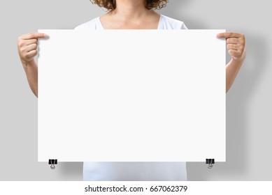 Woman Holding A Blank A2 Poster Mockup Isolated On A Gray Background.