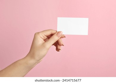 Woman holding blank business card on pink background, closeup. Mockup for design