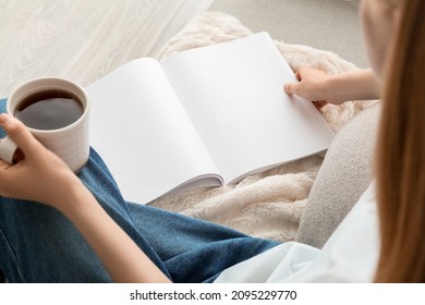 Woman holding blank magazine and cup of tea on light background