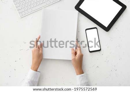 Woman holding blank magazine on light background