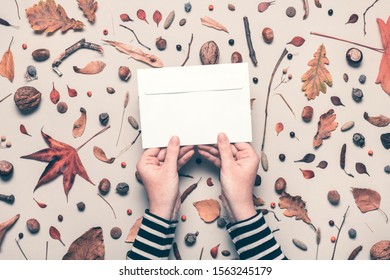 Woman Holding Blank Post Mail Envelope Mock Up With Autumn Arrangement Flat Lay Top View Copy Space