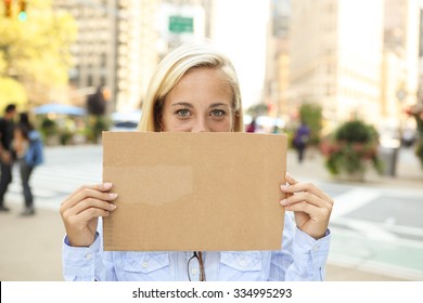 A Woman Holding Up A Blank Sign In Front Of Her Face.