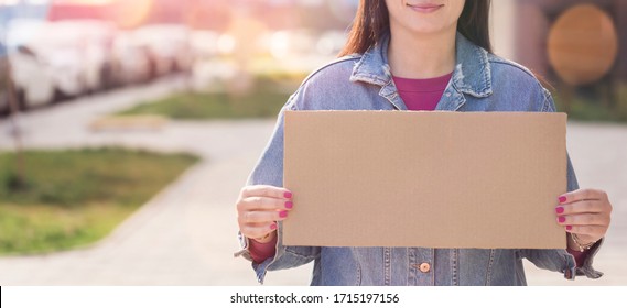 Woman holding blank sign in hands standing on the stree