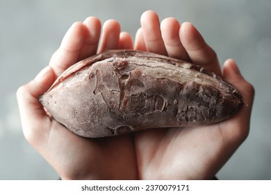 woman holding boiled sweet potato with both hands top up view. concept photo about famine and food crisis - Shutterstock ID 2370079171
